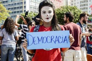 Brazilian protestor holding a sign reading, "Democracia."