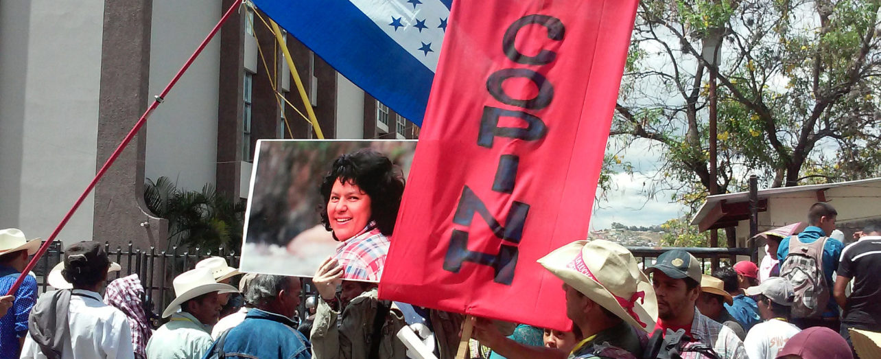 COPINH members march with banner and photo of Berta