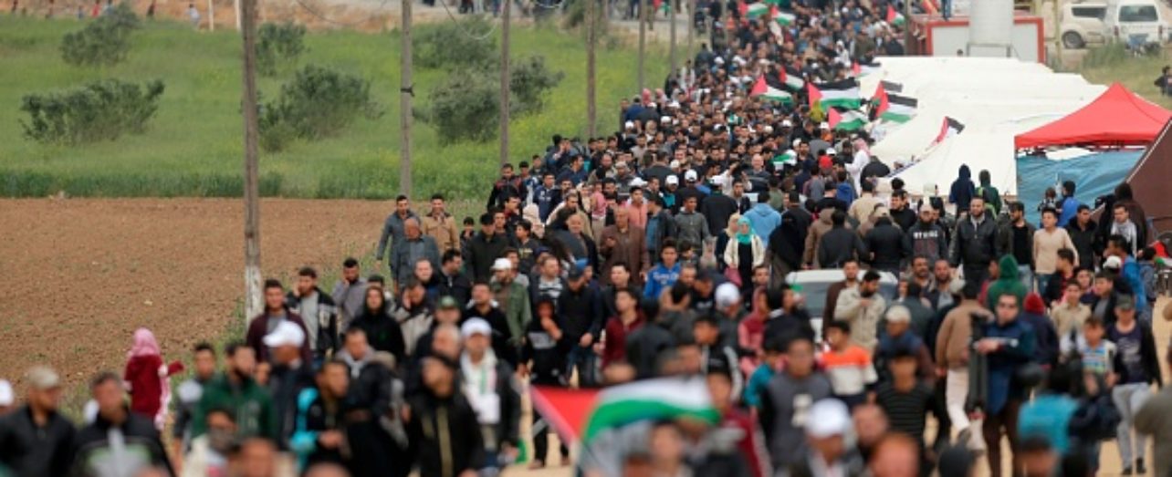 A picture taken on March 30, 2018 shows Palestinians marching past a tent city erected along the border with Israel east of Gaza City in the Gaza strip to commemorate Land Day. Land Day marks the killing of six Arab Israelis during 1976 demonstrations against Israeli confiscations of Arab land.