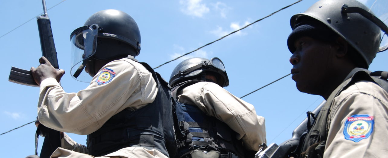 The government in Haiti is repressing protests. In this photo from 2010, National Police are armed with machine guns as they observe a march.